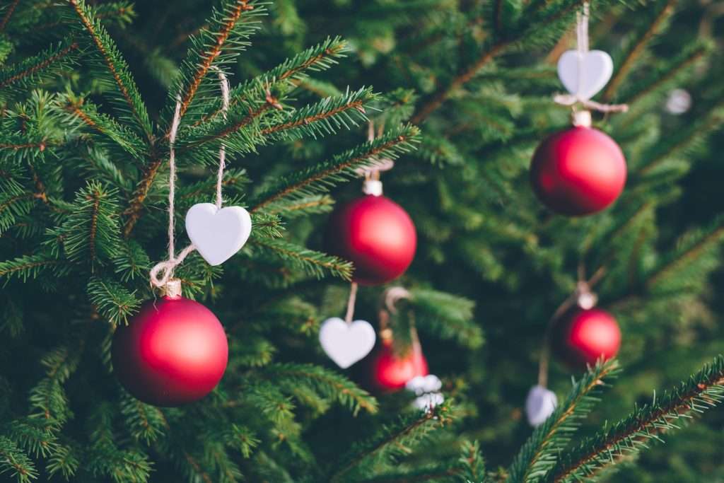 A fir tree with decorations consisting of red bulbs and white hearts.